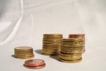 Стопки золотистых и медных монет на белой ткани