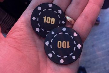 Две чёрные покерные фишки номиналом 100 на раскрытой ладони